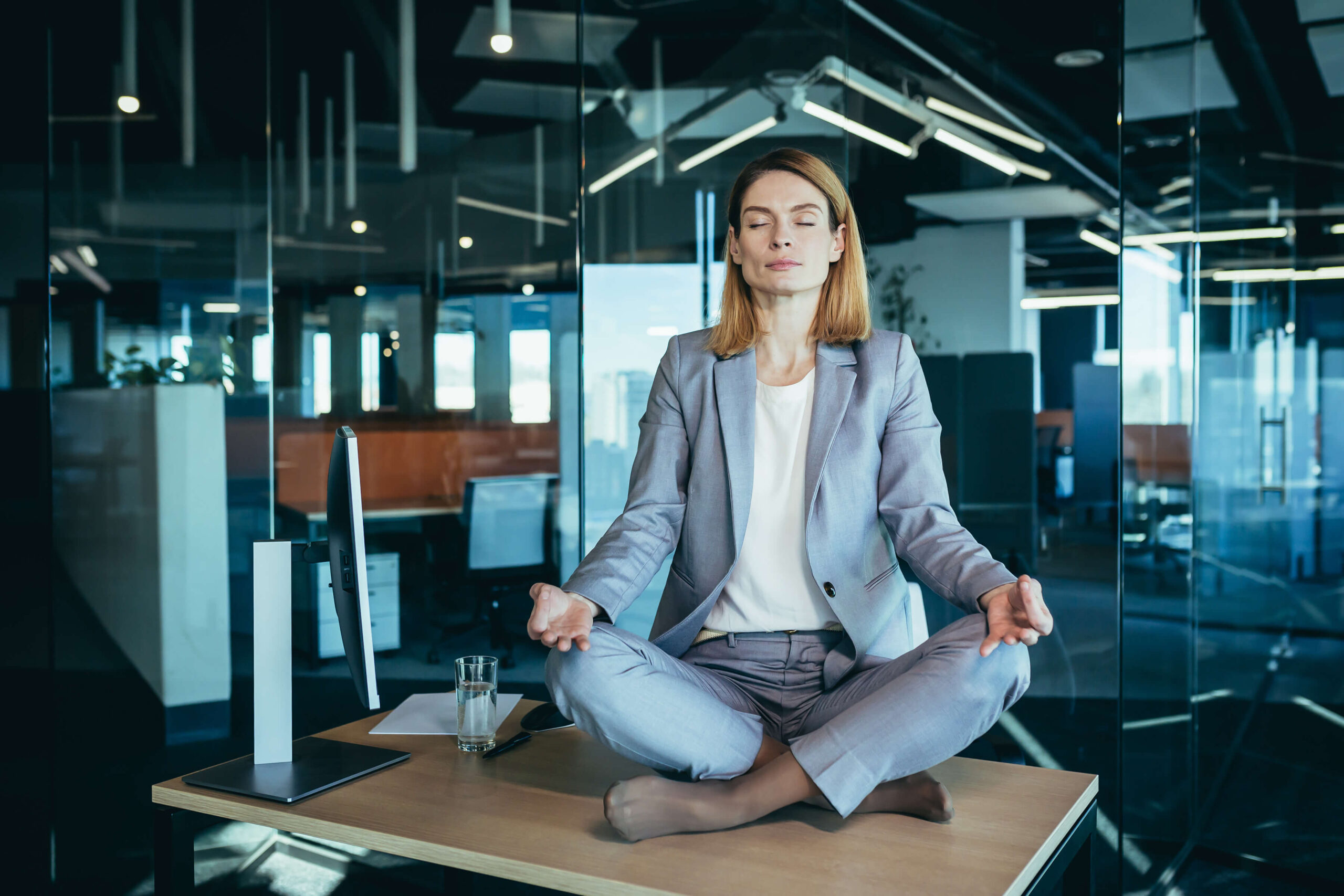 Business woman alone sitting at desk in her office, female employee meditating in lotus position