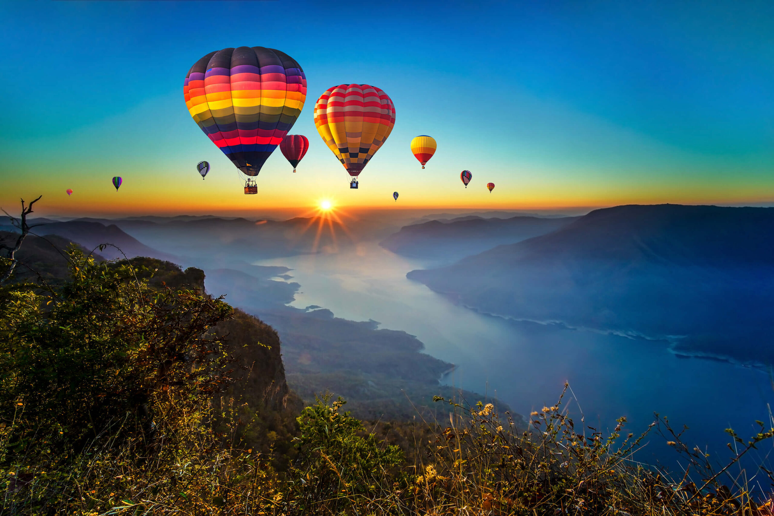 Colorful hot air balloons flying over mountain and Ping River at Pha Daeng Luang, Mae Ping National Park, Lamphun in Thailand
